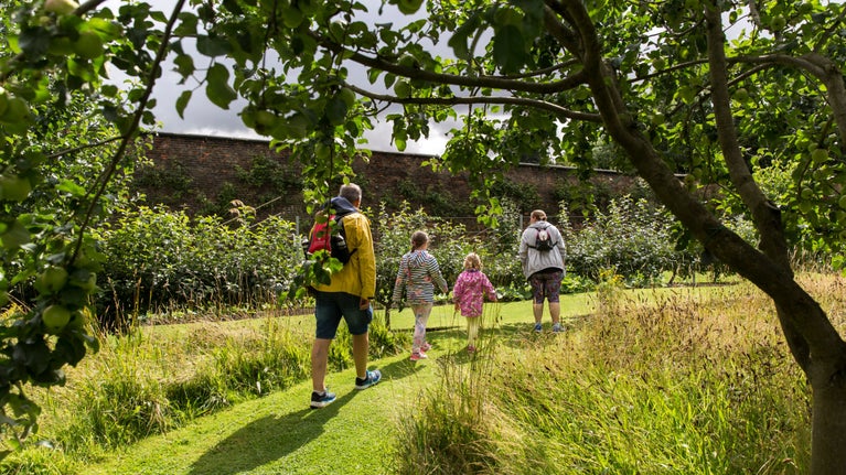 Family walking through the orchard in the gardens at Nostell
